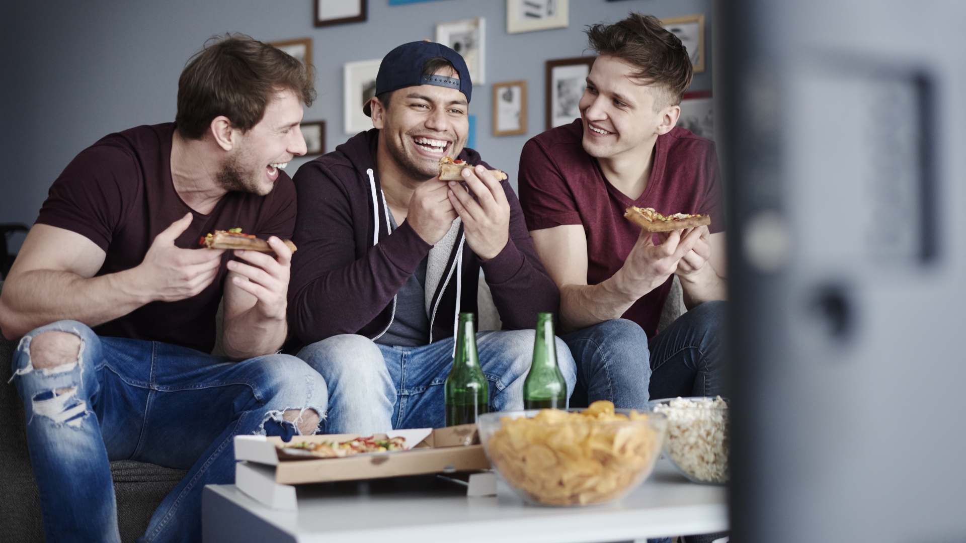 Drei junge Männer schauen Fernsehen Drei junge Männer schauen Fernsehen